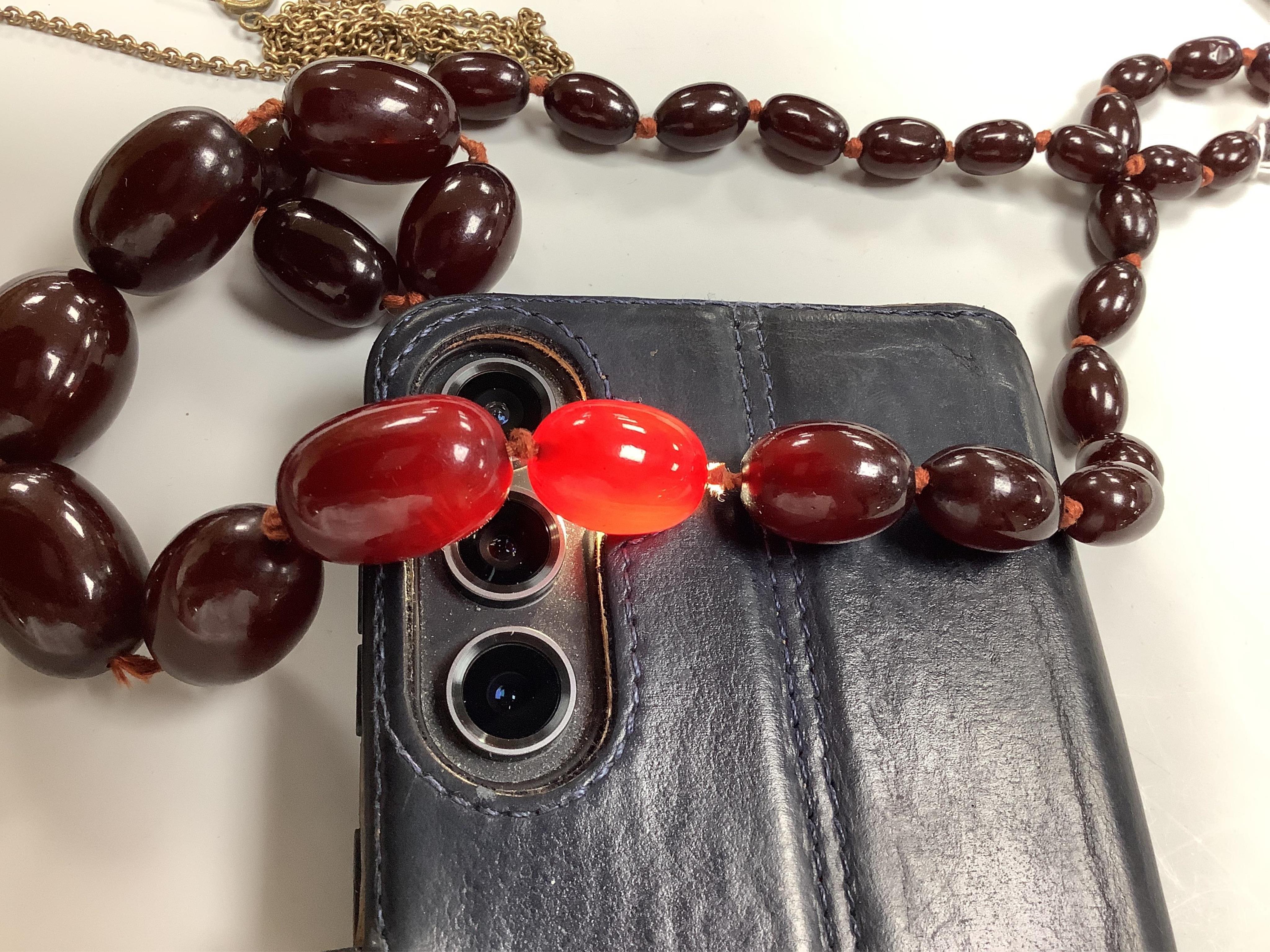 A cherry bakelite 'amber' necklace and pendant, comprising: a necklace composed of cherry-coloured bakelite beads measuring approximately 10 - 26mm, length 90cm, gross weight 72 grams; and a drop-shaped pendant, length 5